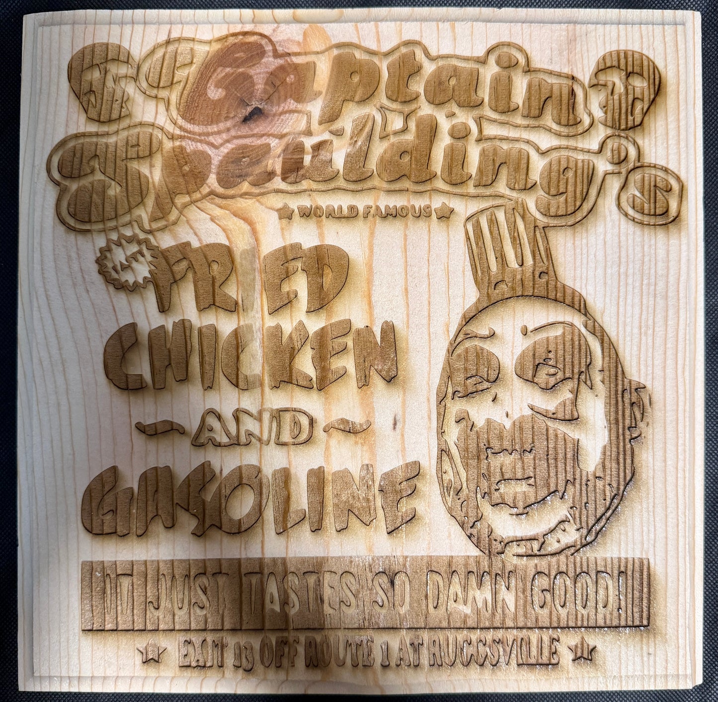 Wooden sign with laser-cut text and skull design, featuring 'Captain Spaulding's' and 'Fried Chicken and Gasoline'.